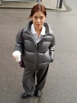 A woman on a wet pavement in a puffer jacket and boots